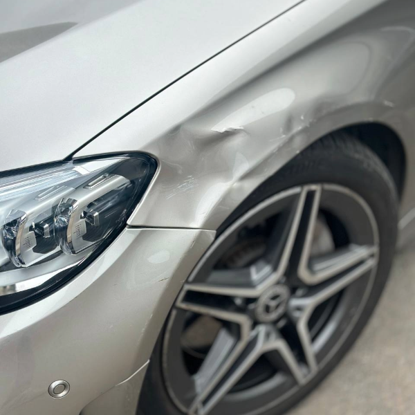 Front wing dent before car body repair Burton-on-Trent on silver Mercedes